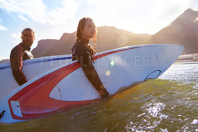 Buy stock photo Shot of an athletic young couple surfing at their favourite beach