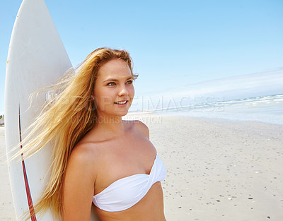 Buy stock photo Shot of a beautiful young woman standing on the beach with her surfboard