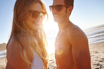 Buy stock photo Shot of a young couple enjoying the late afternoon sun at the beach