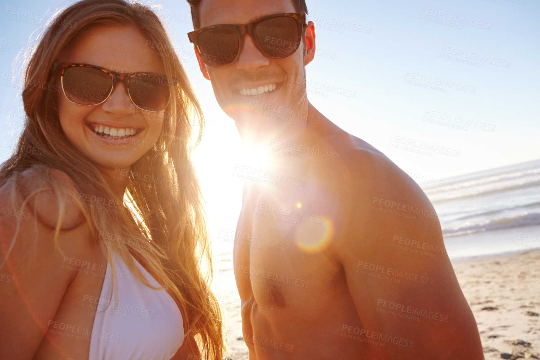 Buy stock photo Portrait of a young couple enjoying the late afternoon sun at the beach