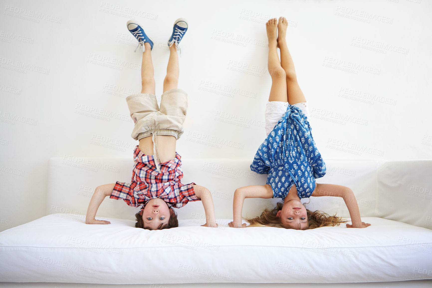 Buy stock photo Shot of a playful young brother and sister doing handstands together on the sofa