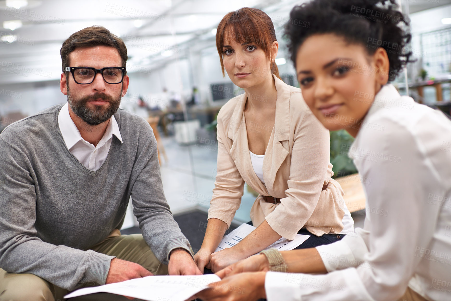 Buy stock photo Shot of a group of young professionals discussing paperwork