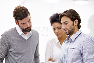 Buy stock photo Shot of three young businesspeople standing in his office and talking over a tablet