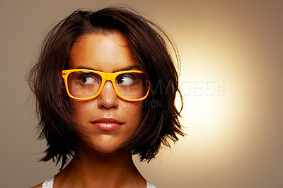 Buy stock photo An attractive edgy young woman wearing funky yellow glasses against a brown background. A young stylish confident woman with short brunette hair looking sideways against a brown studio background
