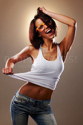 Buy stock photo Cropped studio shot of an attractive young woman pulling at her tank top