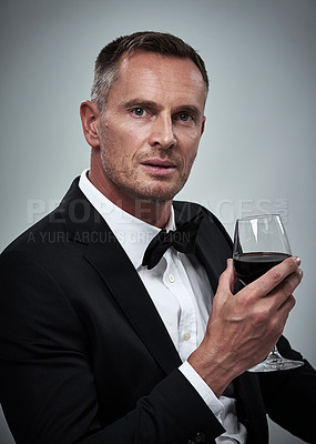 Buy stock photo Tuxedo, red wine and spy man with alcohol in a suit feeling classy with a luxury drink. Gray background, isolated and studio with a model, agent or actor with a glass and rich person with mockup