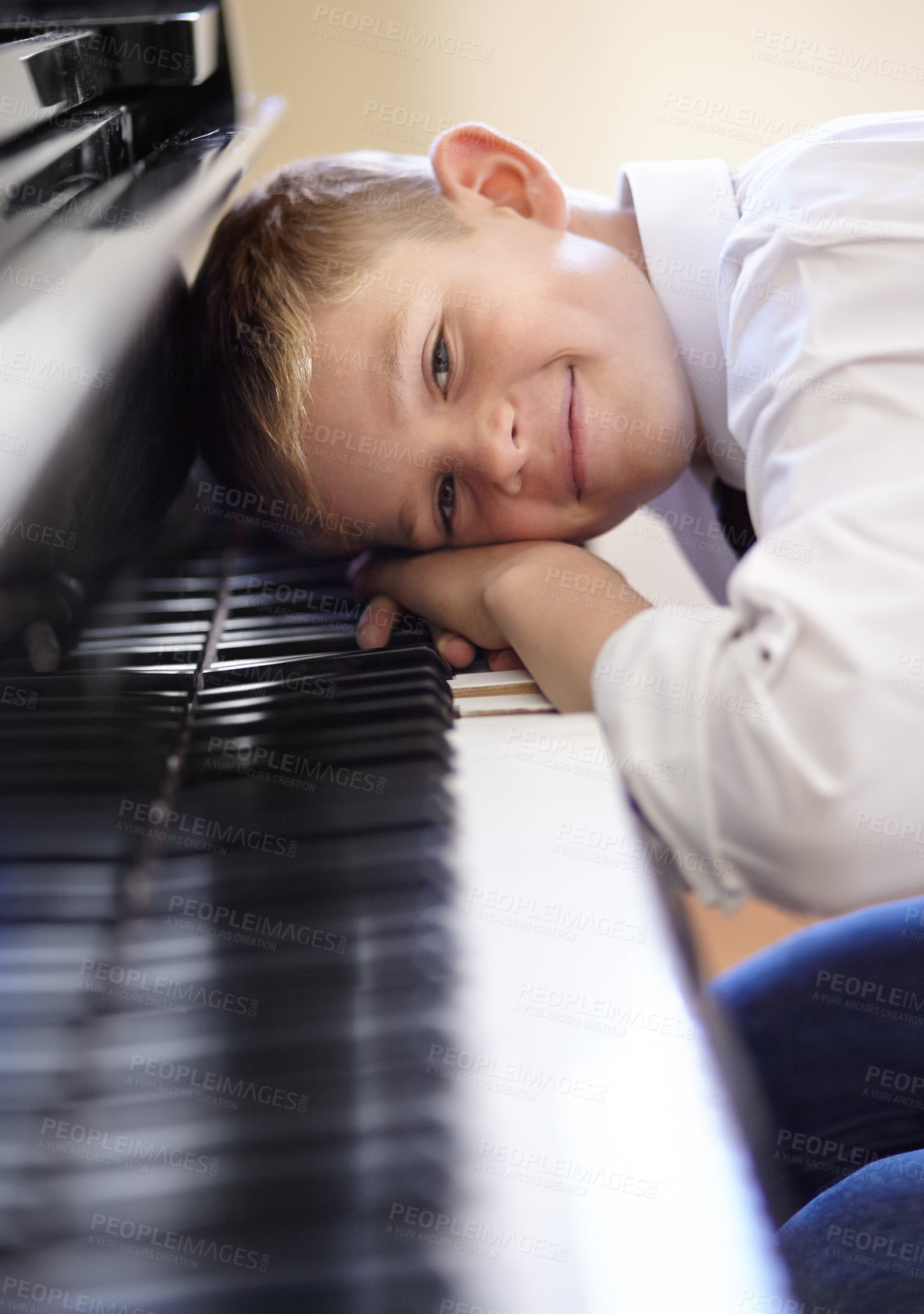 Buy stock photo Young piano student leaning on the keys of his piano