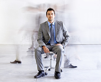Buy stock photo Portrait, chair and a corporate man in a busy office with motion blur people walking for company productivity. Work, business and professional with a young employee in a suit sitting in the workplace