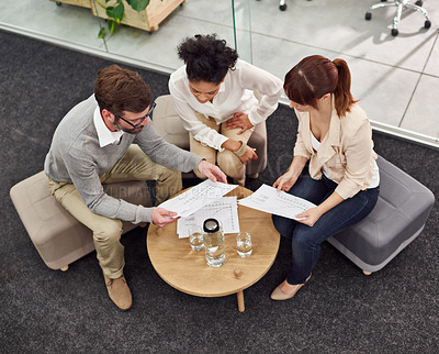 Buy stock photo Shot of a group of young professionals discussing paperwork