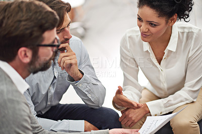 Buy stock photo Shot of a group of young professionals discussing paperwork