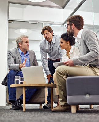 Buy stock photo Shot of a diverse group of office professionals talking around a laptop