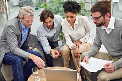 Buy stock photo Shot of a diverse group of office professionals talking around a laptop