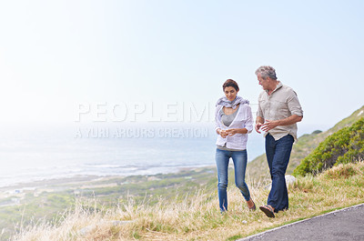 Buy stock photo Holiday, walk and mature couple on road at the beach in countryside or nature with conversation of retirement. Summer, vacation and old man with woman talking on grass together at sea or ocean mockup