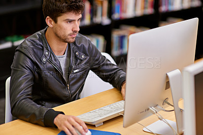 Buy stock photo Shot of a male student working on a computer in a university library
