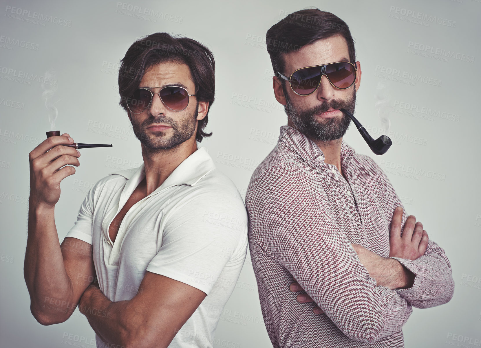 Buy stock photo Studio shot of two men standing together while wearing retro 70s wear and smoking pipes