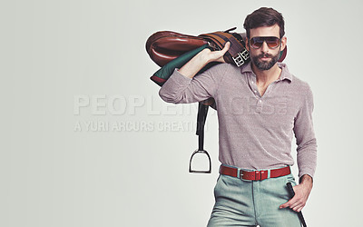 Buy stock photo Studio shot of an attractive man in retro 70s wear holding a saddle and riding crop