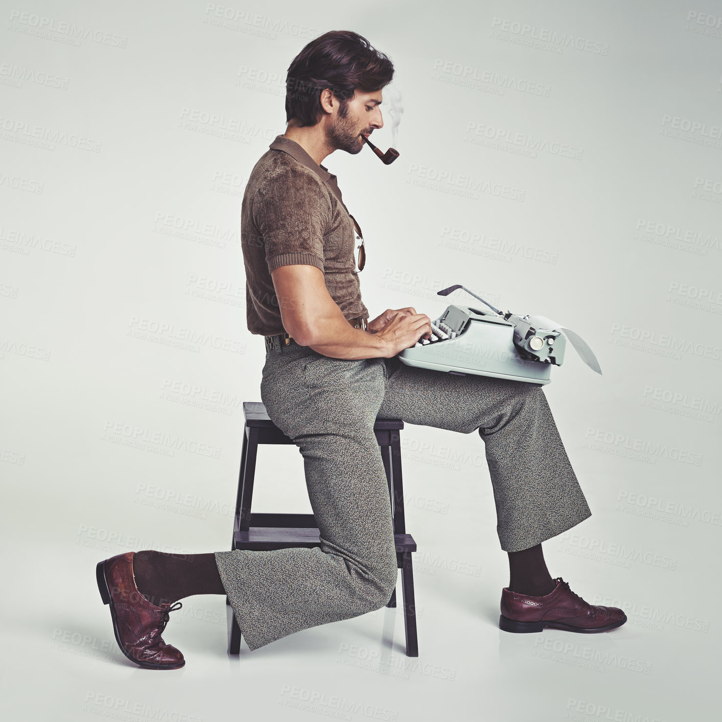 Buy stock photo Studio shot of a 70's style businessman sitting on a stool using a typewriter