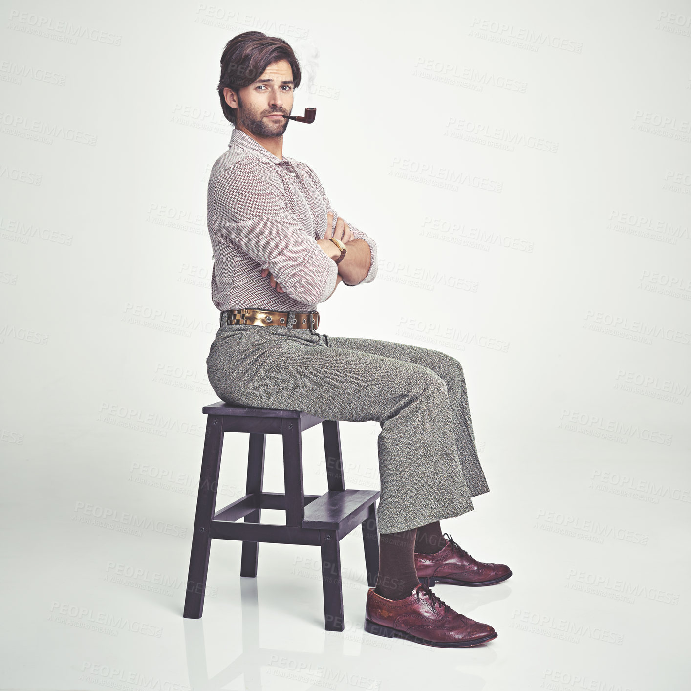 Buy stock photo A young man with 70s style sitting in the studio and smoking a pipe