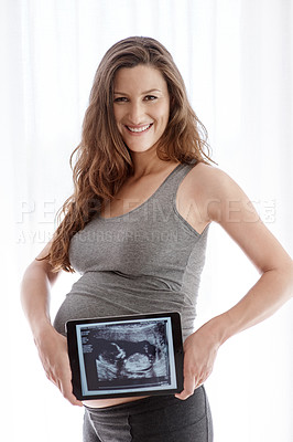 Buy stock photo Shot of a young pregnant woman holding a digital tablet with her ultrasound on the screen