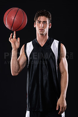 Buy stock photo Portrait of a young sportsman spinning a basketball on his finger against a black background