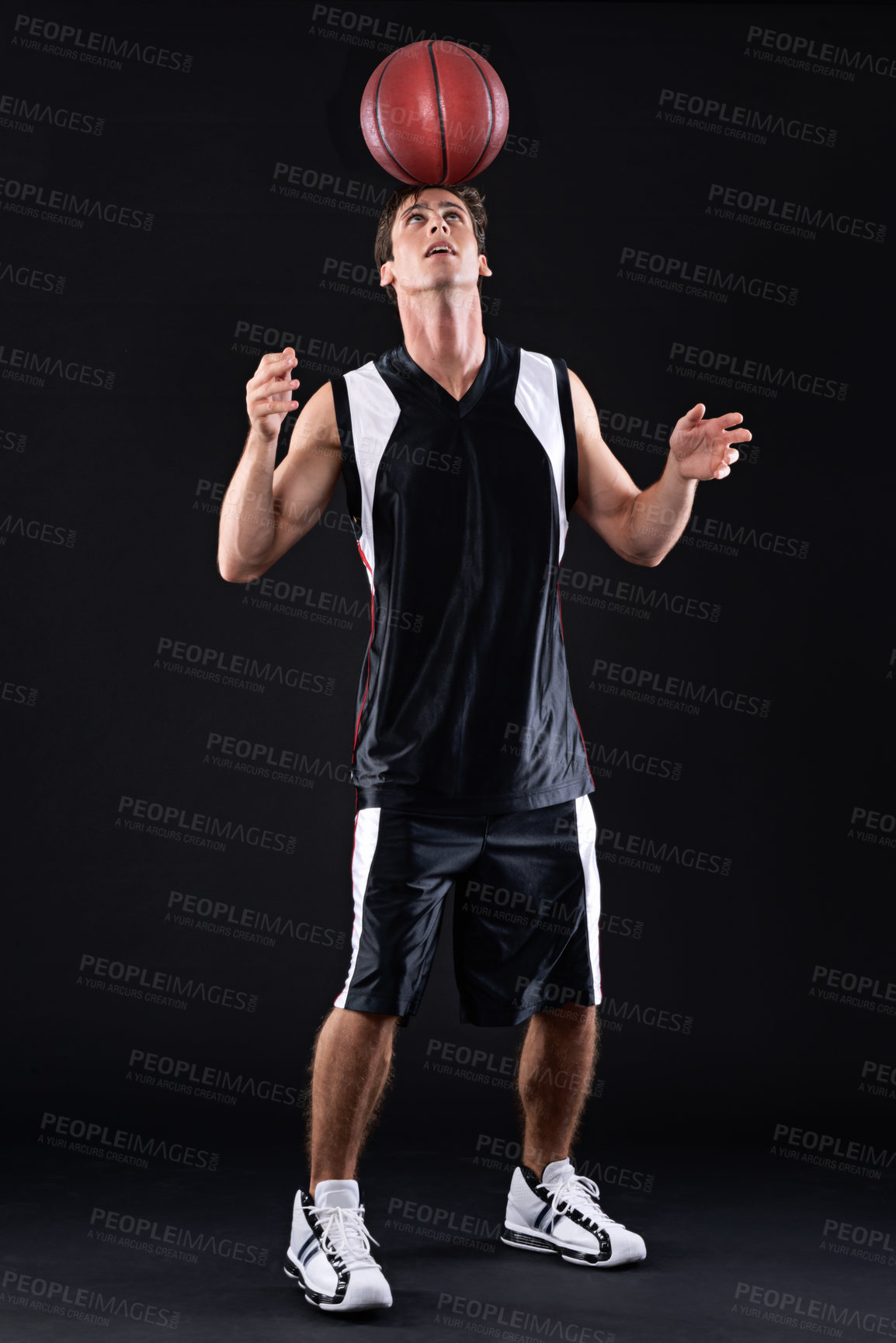 Buy stock photo Shot of a male basketball player balancing the ball on his head against a black background