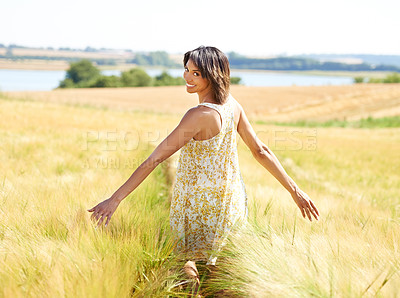 Buy stock photo Back, freedom and portrait of happy woman at field in the countryside outdoor in summer. Rear view, person in nature and open arms at farm, grass and smile on vacation, holiday and travel in Brazil