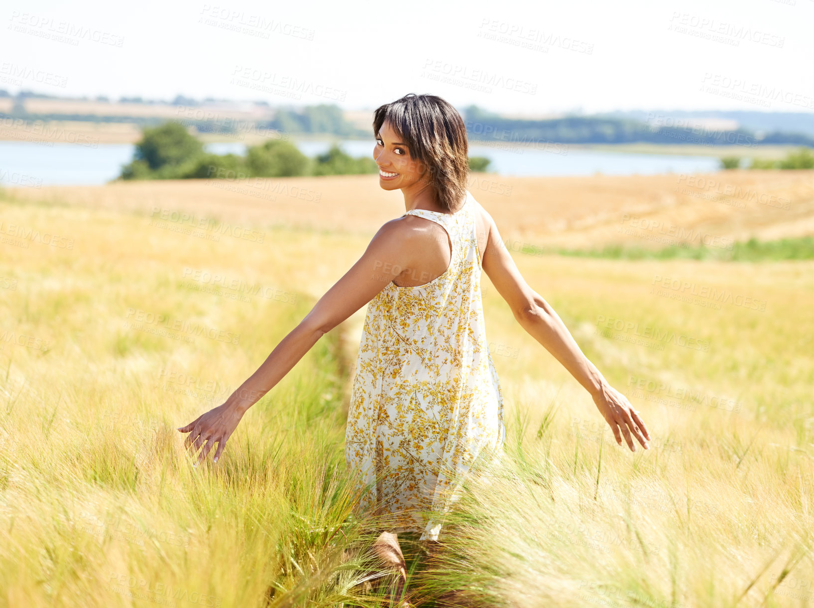 Buy stock photo Back, freedom and portrait of happy woman at field in the countryside outdoor in summer. Rear view, person in nature and open arms at farm, grass and smile on vacation, holiday and travel in Brazil