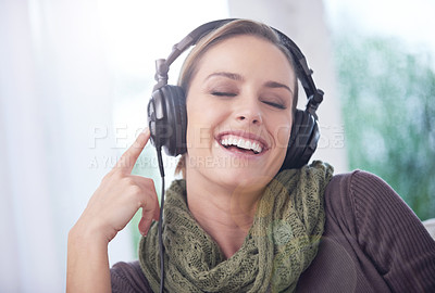 Buy stock photo Home, funny and woman with headphones, listening to radio and peaceful with weekend break and calm. Apartment, laughing and person on sofa and headset for audio, sound and streaming music with humor