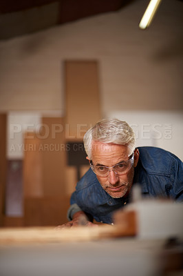 Buy stock photo Carpenter, mature man and working with wood in workplace of workshop as construction worker in company. Employee, male person and professional thinking with glasses for safety in garage and shop