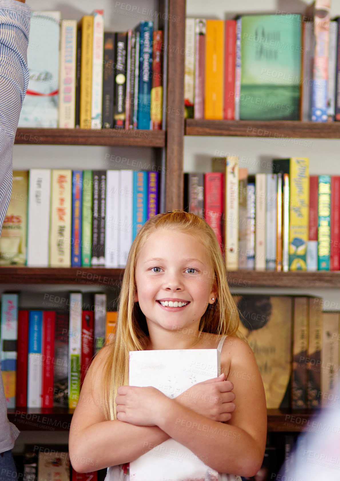 Buy stock photo A cute young girl clutching her book in a library