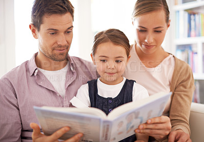Buy stock photo Parents, child and reading at home, sofa and child development in home schooling and bonding. Mom, dad and toddler on couch, living room and smile while learning in book and fairytale stories 