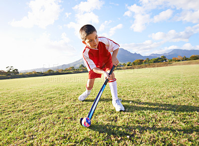 Buy stock photo Child, ball and playing hockey on green grass for game, sports or outdoor practice match. Young kid or player enjoying day on field for fitness, activity or training alone in nature with blue sky