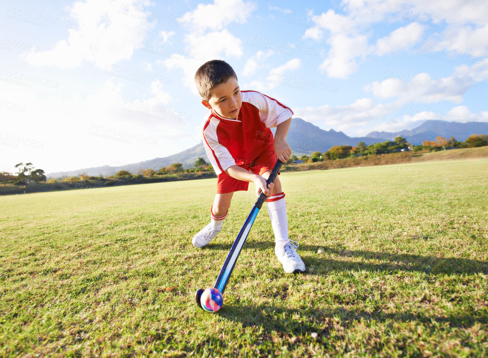 Buy stock photo Child, ball and playing hockey on green grass for game, sports or outdoor practice match. Young kid or player enjoying day on field for fitness, activity or training alone in nature with blue sky