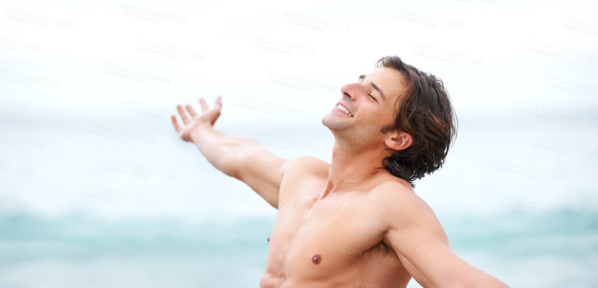 Buy stock photo Shot of a handsome young man enjoying an amazing day at the beach