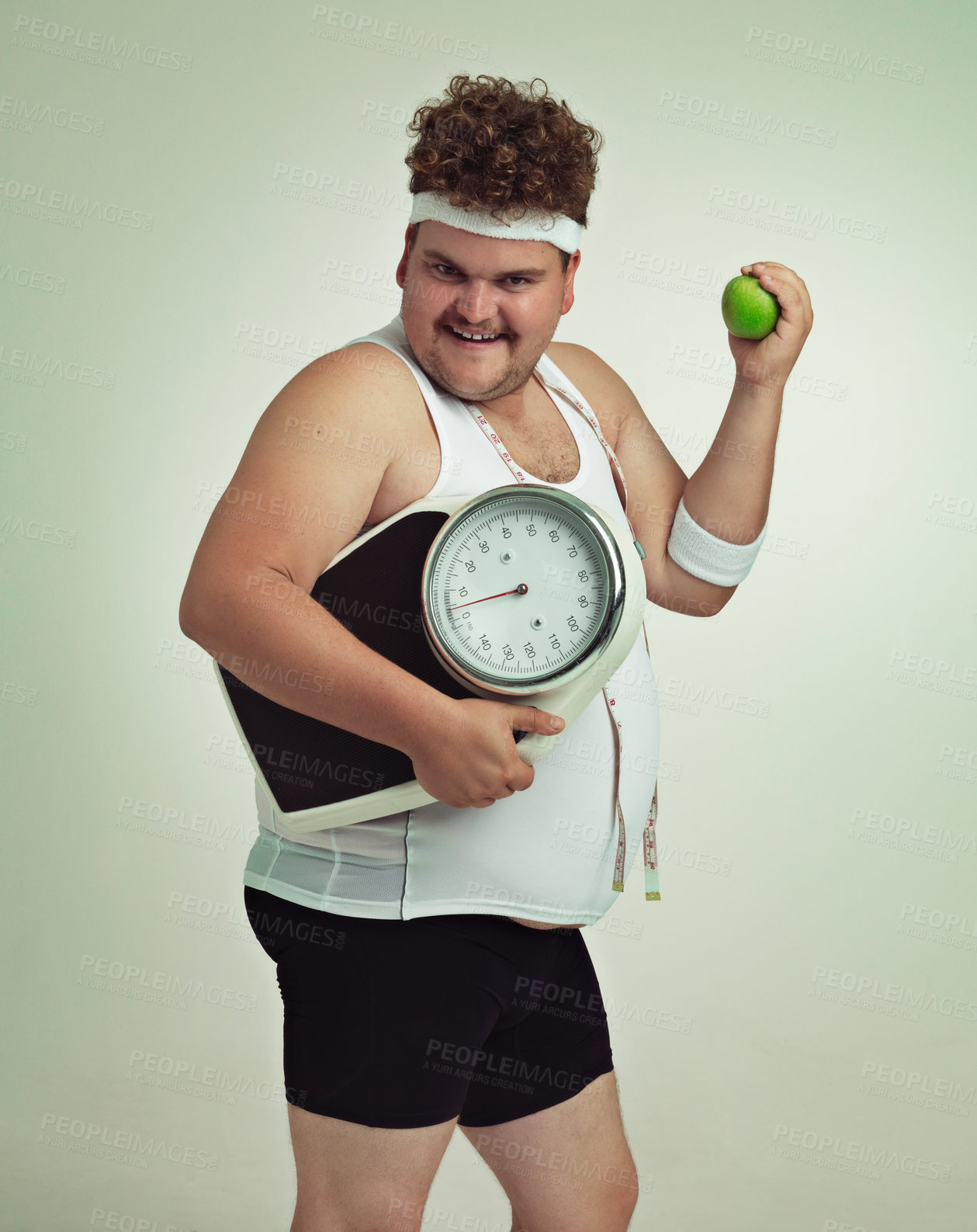 Buy stock photo Cropped shot of an overweight man holding a apple,scale and measuring tape