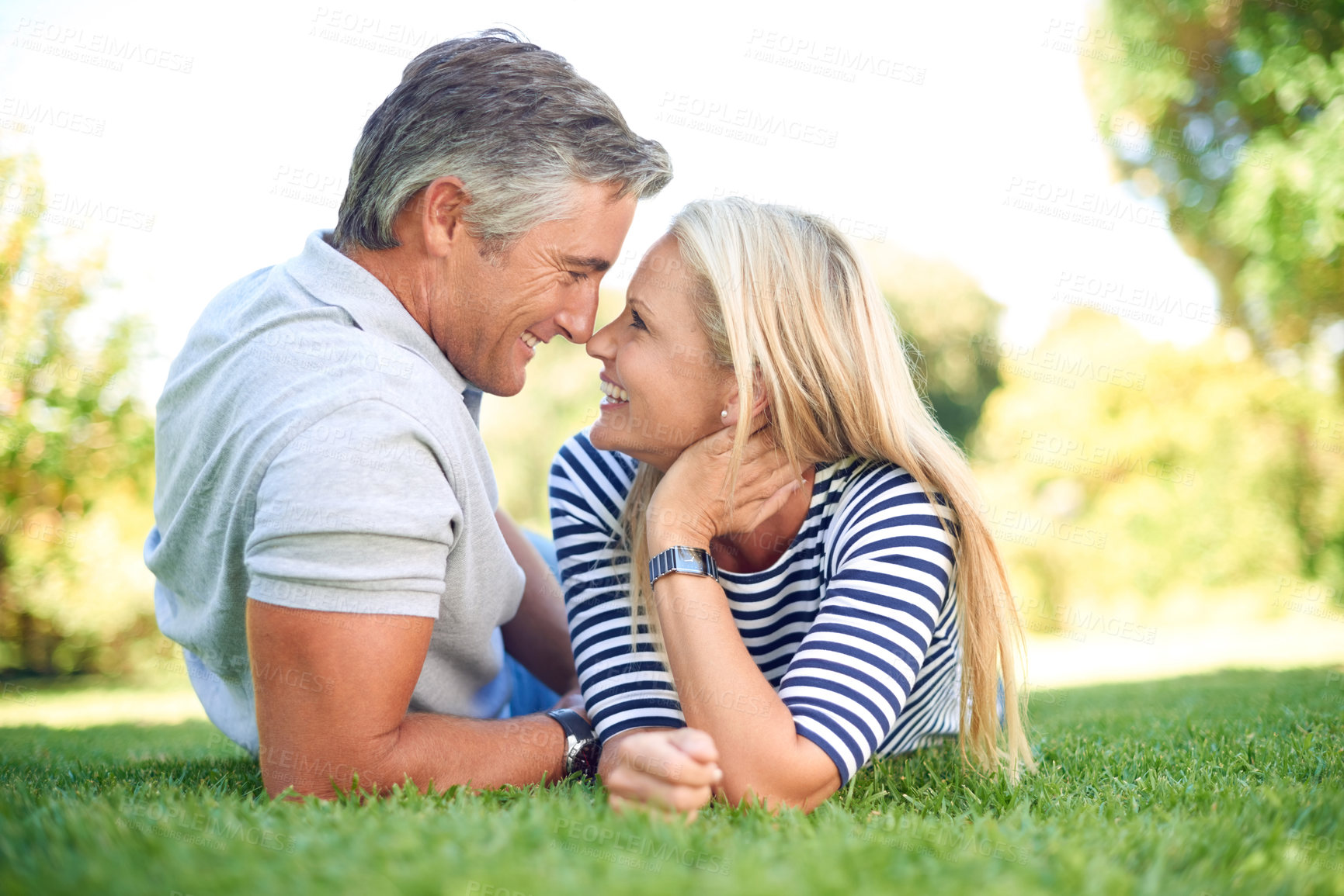 Buy stock photo Nose touch, smile and couple on grass outdoor at park for love, care and romantic date. Happy woman, mature man and relax on lawn for connection, partnership and bonding together for relationship