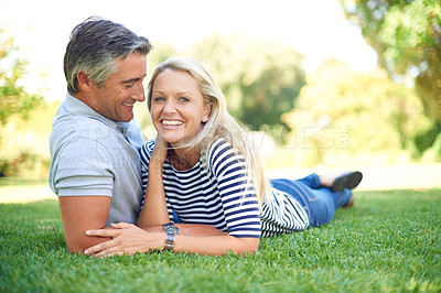 Buy stock photo Full length portrait of an affectionate mature couple lying in the park