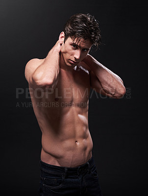 Buy stock photo Studio shot of a handsome bare-chested young athlete standing against a black background