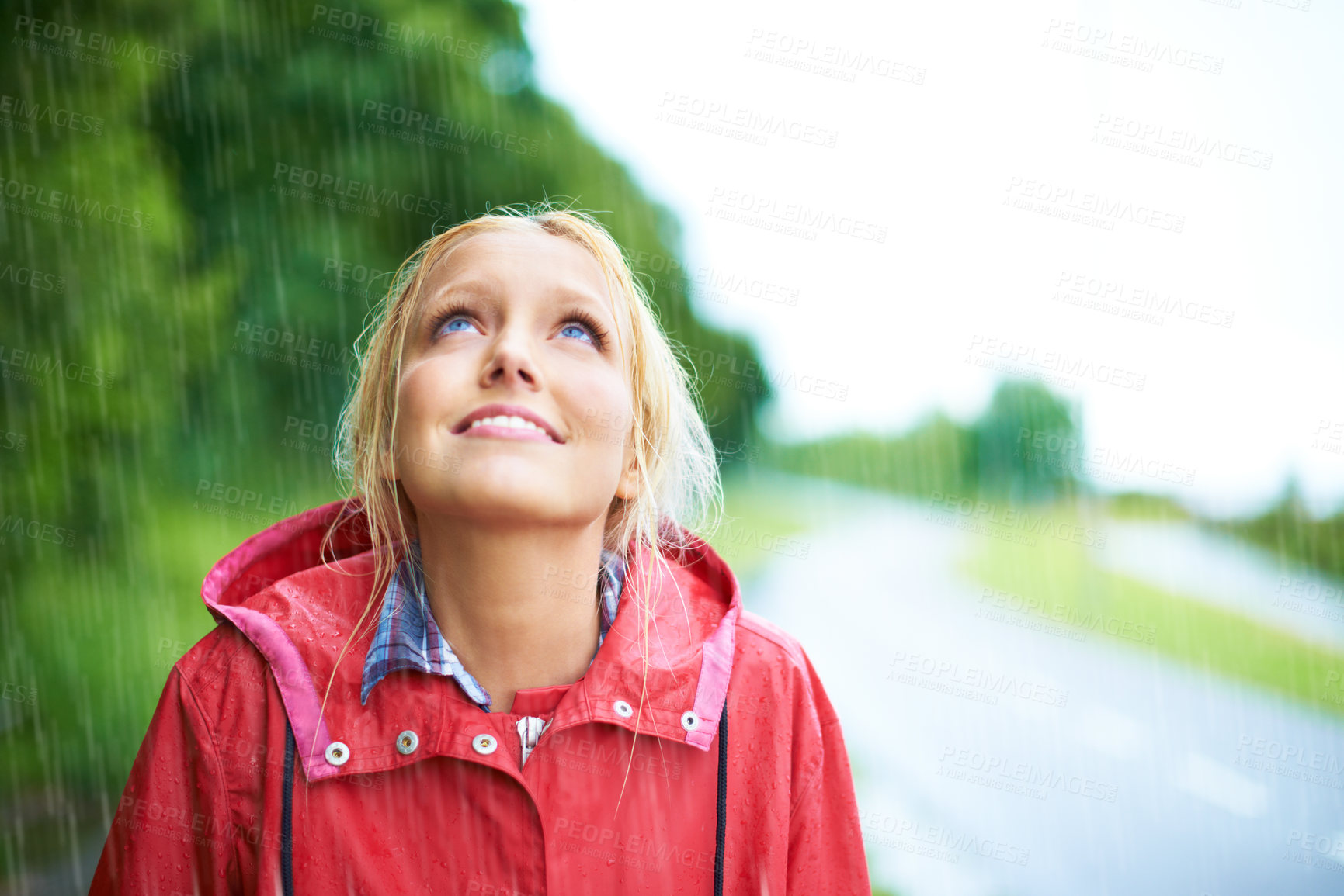Buy stock photo Woman, smile and raincoat in outdoor rainfall, wet and cold from weather, winter and nature. Happy female person, fashion and red jacket is cool, rain and looking up to sky by water, face and holiday