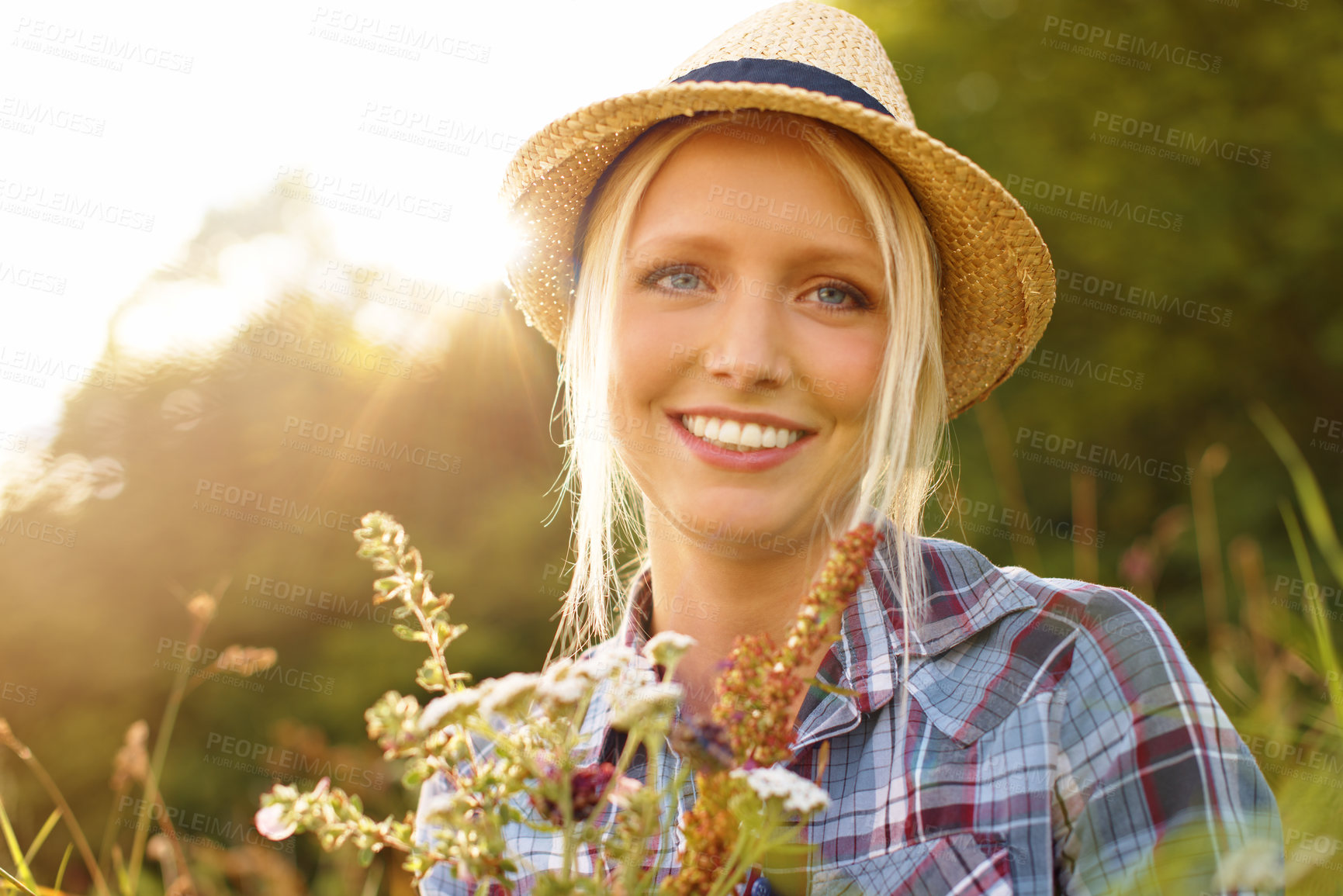 Buy stock photo Countryside, flowers and portrait of woman in field for sustainability, wellness and fresh air outdoors. Nature, summer and face of hipster person in meadow to relax, calm and peace with lens flare