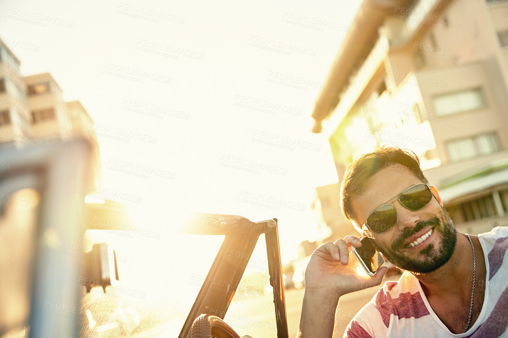 Buy stock photo Shot of a young man sitting in his car while talking on his cellphone