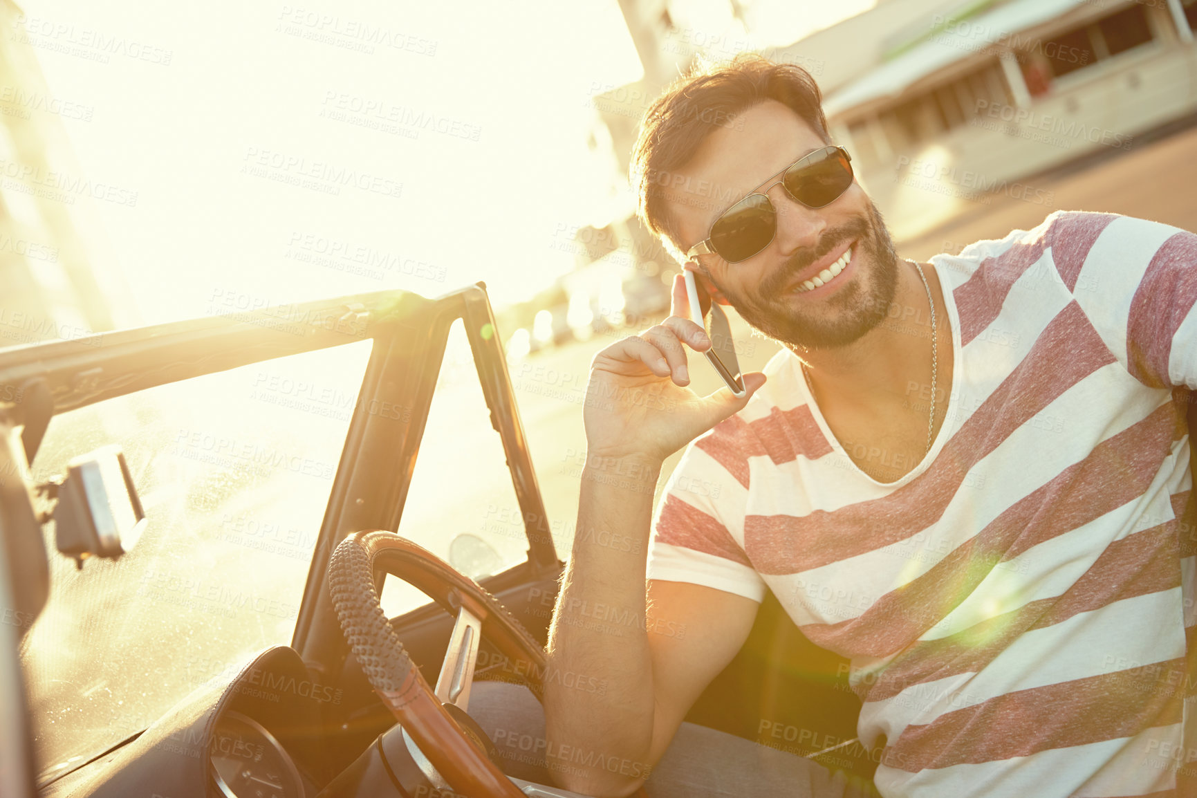 Buy stock photo Shot of a young man sitting in his car while talking on his cellphone