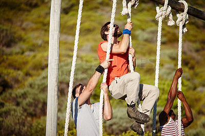 Shot of a group of men climbing up ropes at a military bootcamp