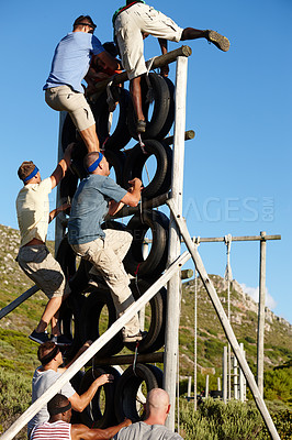 Buy stock photo Shot of a group of men climbing over an obstacle at a military bootcamp