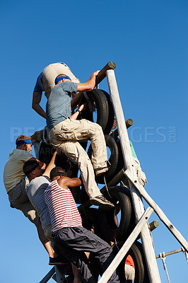 Buy stock photo Shot of a group of men climbing over an obstacle at a military bootcamp
