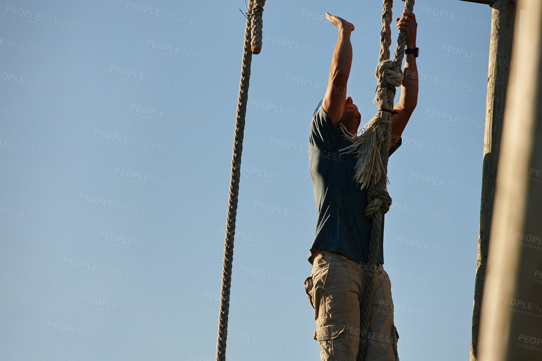 Buy stock photo Shot of a man climbing up a rope at a military bootcamp