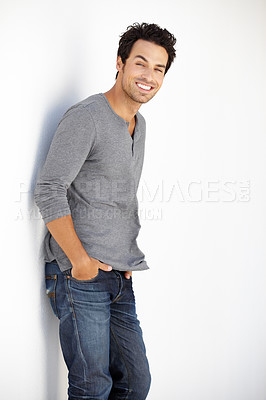 Buy stock photo Portrait of a handsome young man standing against a white wall with his hands in his pockets