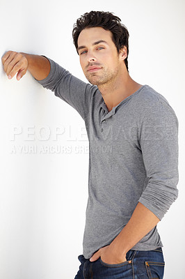 Buy stock photo Portrait of a handsome young man leaning with his arm against a white wall