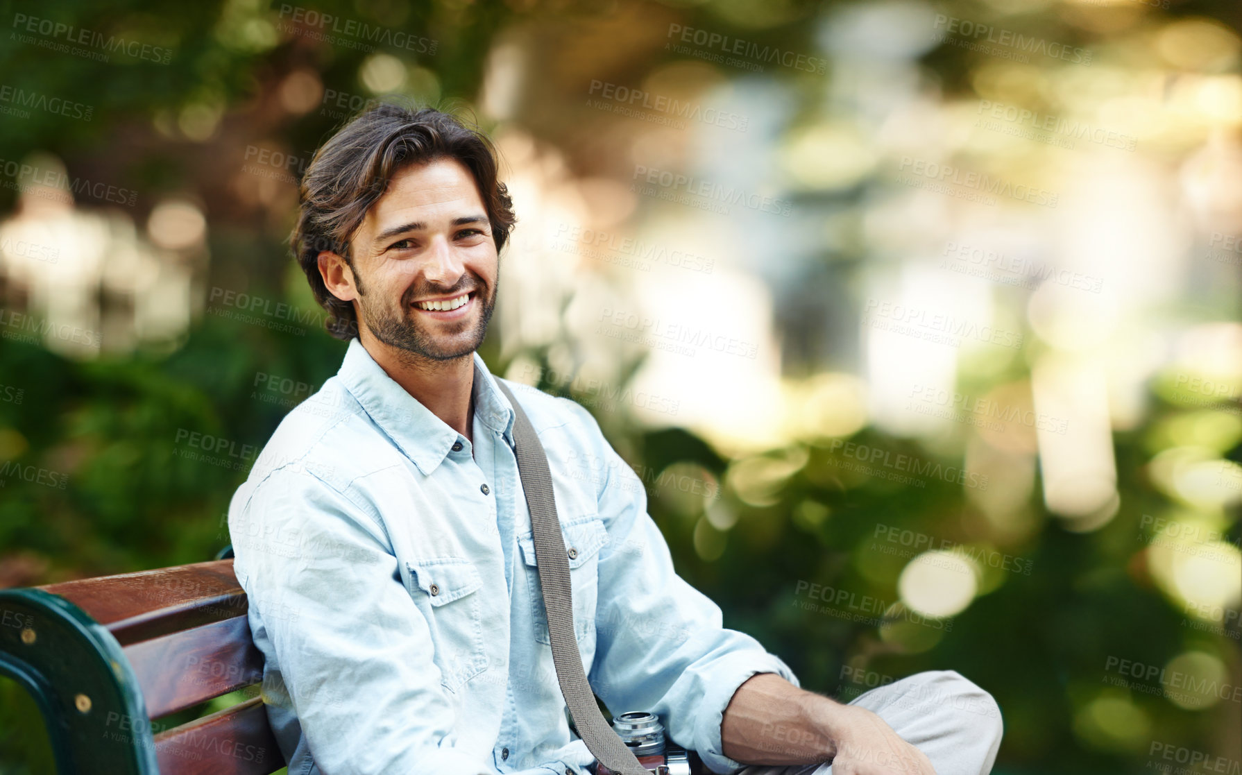 Buy stock photo Nature, relax and portrait of a man on a park bench for a break, morning commute or travel. Smile, summer and a young person or tourist in a public garden for tourism, sightseeing or a vacation