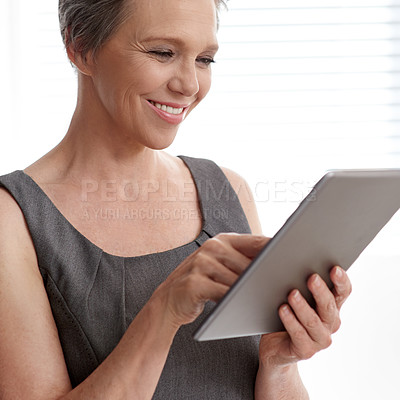 Buy stock photo A mature businesswoman using her digital tablet in the office
